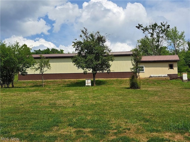 view of home's exterior with an outbuilding, metal roof, and a yard