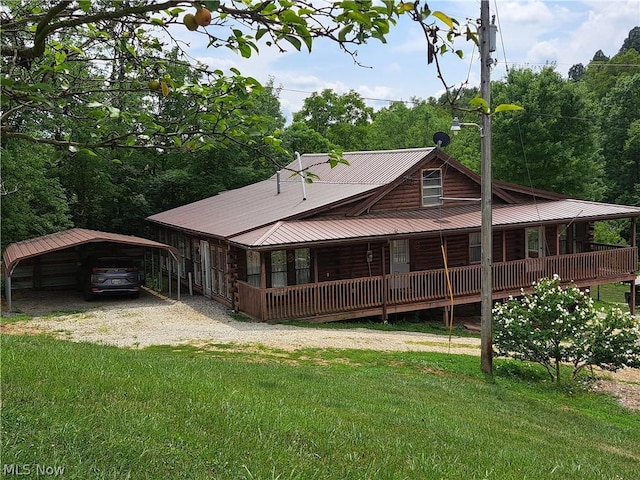 back of house featuring a yard, a detached carport, metal roof, and driveway