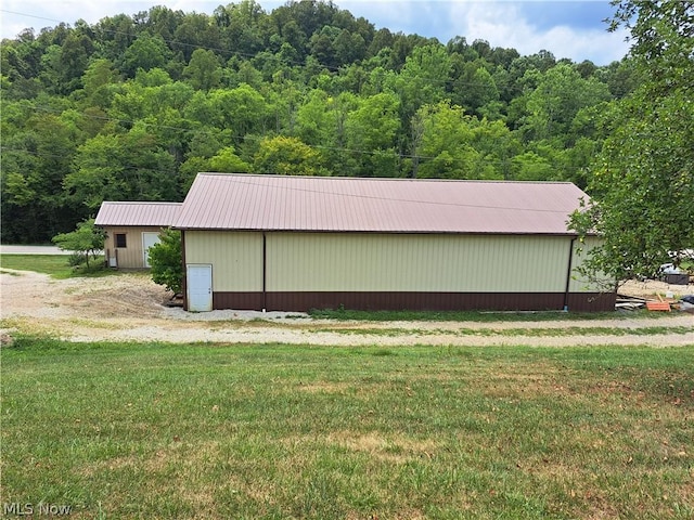 view of pole building with a lawn and a wooded view