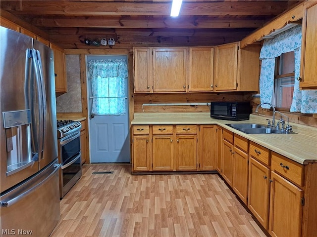 kitchen featuring light wood-style floors, appliances with stainless steel finishes, light countertops, and a sink