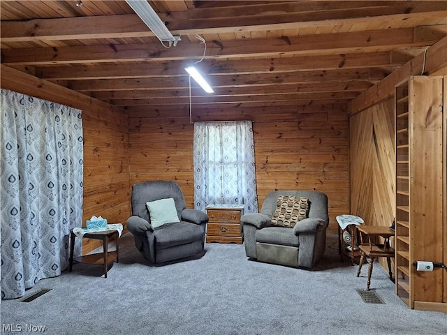 sitting room with beam ceiling, visible vents, wood ceiling, carpet flooring, and wooden walls