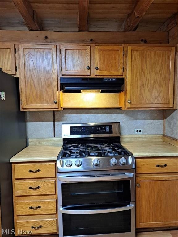 kitchen with under cabinet range hood, double oven range, light countertops, and freestanding refrigerator