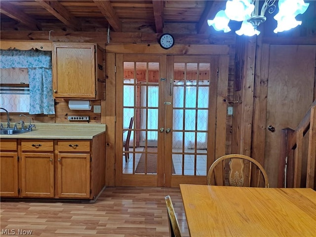 kitchen featuring wooden ceiling, light wood-style flooring, a sink, light countertops, and beam ceiling