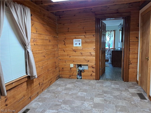 spare room with stone finish flooring, wood walls, and visible vents