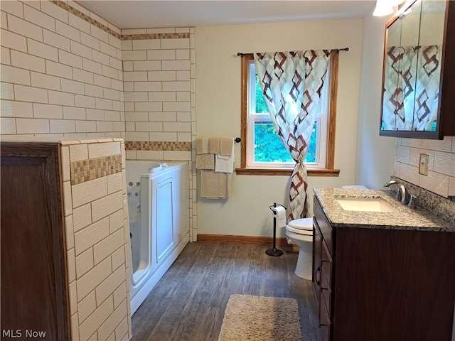 full bath with toilet, wood finished floors, vanity, baseboards, and backsplash