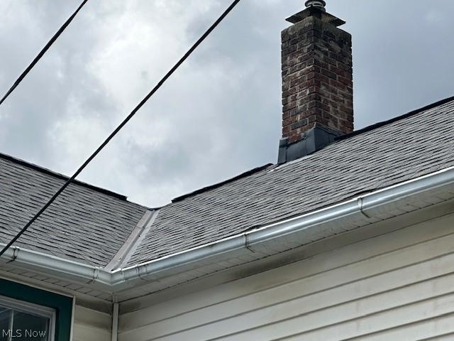 exterior details with a chimney and roof with shingles