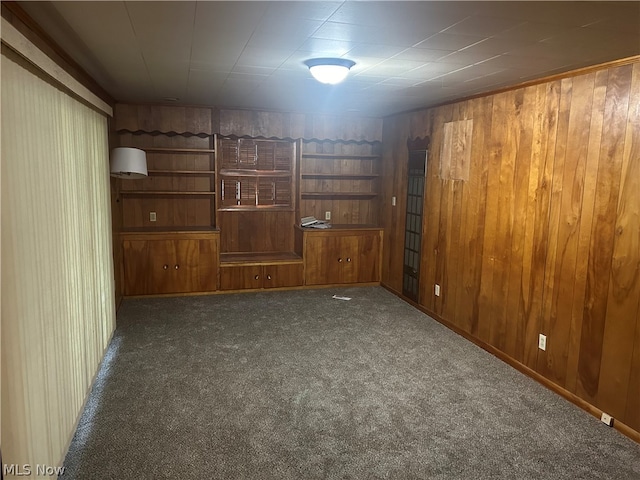 carpeted spare room featuring wooden walls