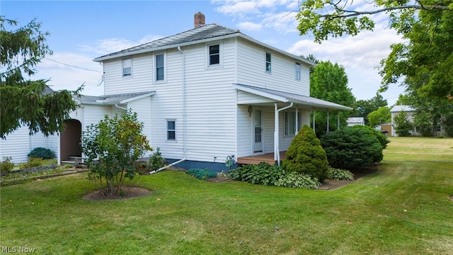 rear view of property featuring a lawn