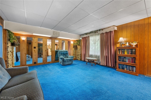 living room with wood walls, carpet, french doors, and a paneled ceiling