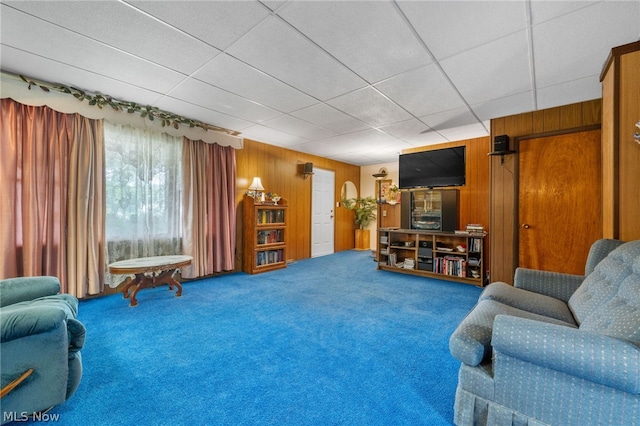 living room featuring a paneled ceiling, carpet, and wooden walls