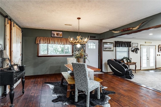 dining room featuring french doors, an inviting chandelier, dark wood-type flooring, and a textured ceiling