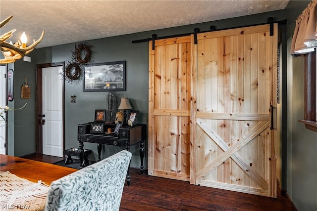 dining room with a textured ceiling, dark hardwood / wood-style flooring, and a barn door