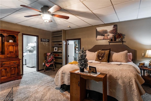 carpeted bedroom featuring a drop ceiling, ensuite bath, ceiling fan, and washer / dryer