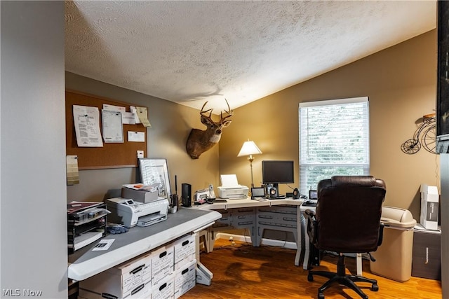 home office with a textured ceiling, vaulted ceiling, and light wood-type flooring