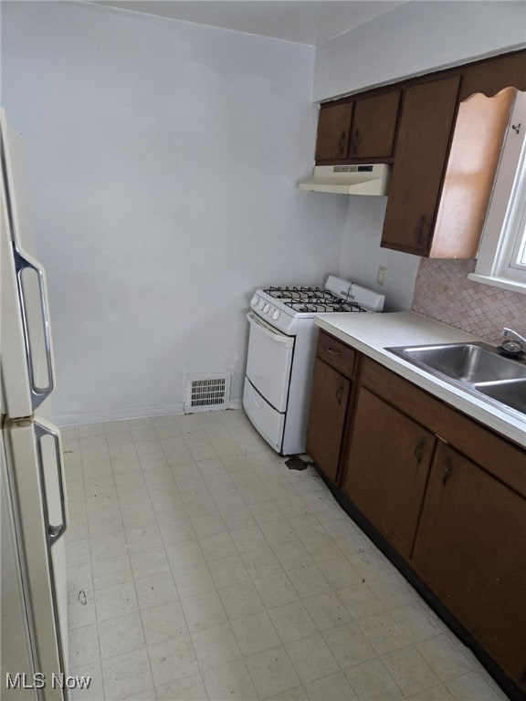 kitchen with sink, dark brown cabinets, and white appliances