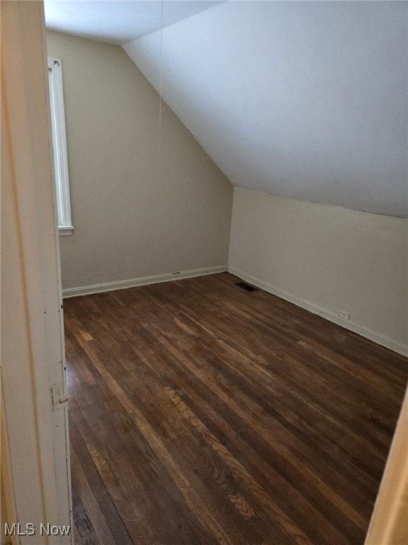 additional living space with vaulted ceiling and dark hardwood / wood-style floors