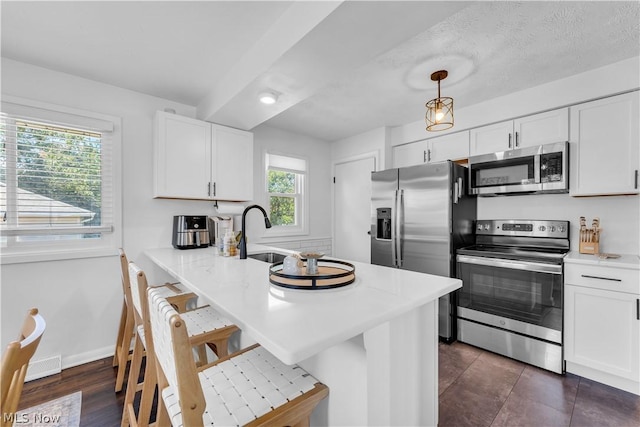 kitchen featuring appliances with stainless steel finishes, decorative light fixtures, white cabinetry, a kitchen breakfast bar, and kitchen peninsula