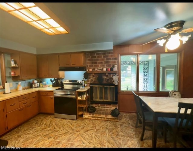 kitchen with brick wall, electric stove, ceiling fan, and light tile patterned floors