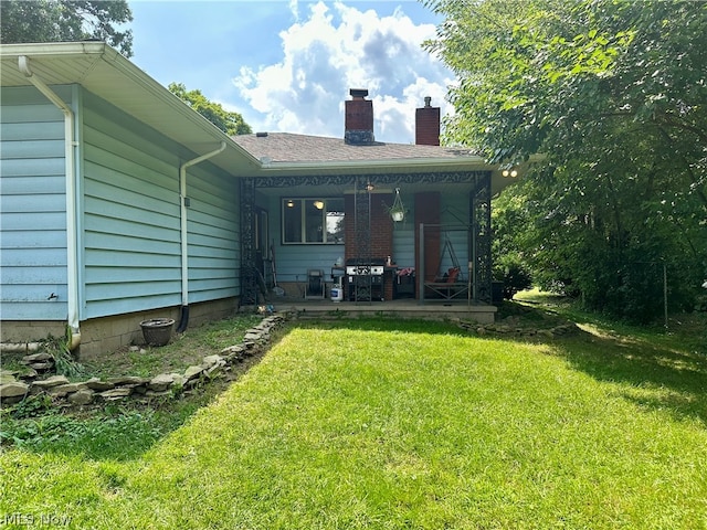 back of property with a lawn and a patio area