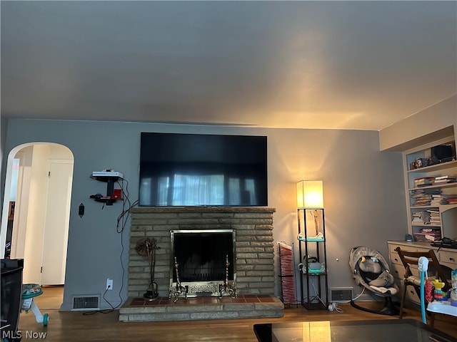 living room featuring a brick fireplace and hardwood / wood-style flooring