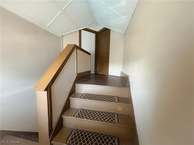 staircase with ornamental molding and lofted ceiling