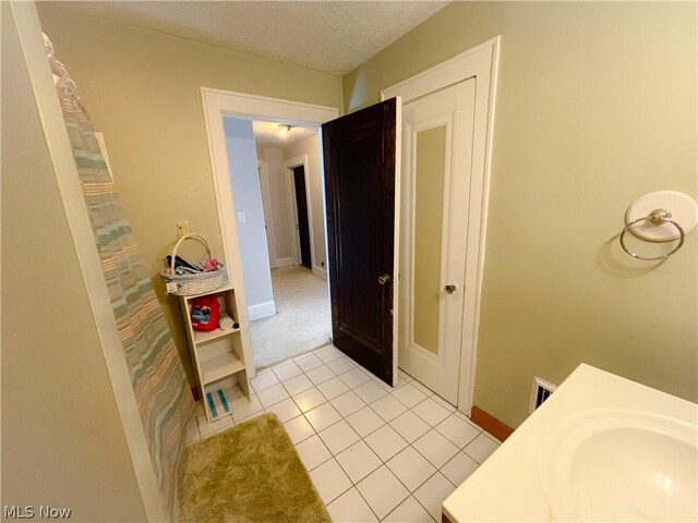 bathroom featuring sink, tile patterned floors, and a textured ceiling