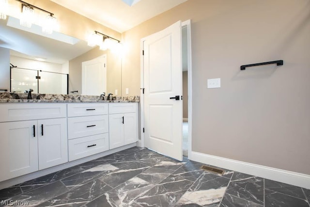 bathroom with marble finish floor, baseboards, double vanity, and a stall shower
