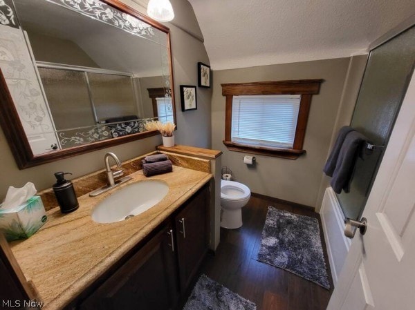 bathroom featuring vaulted ceiling, a textured ceiling, toilet, vanity, and hardwood / wood-style flooring