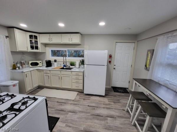 kitchen with sink, light wood-type flooring, and white appliances