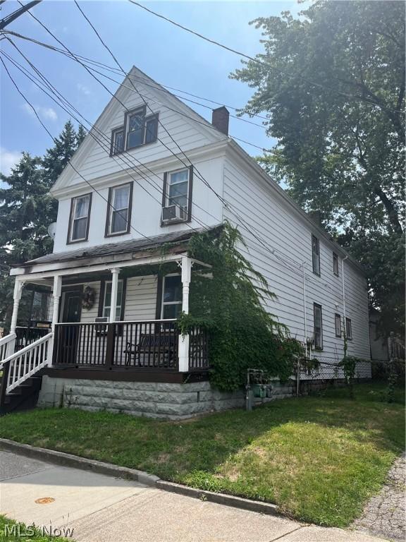 view of front of property with a front yard, covered porch, and cooling unit