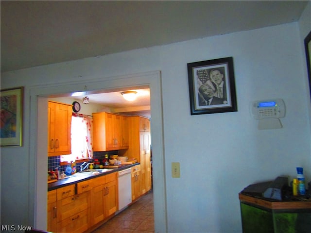 kitchen featuring tile patterned floors, tasteful backsplash, sink, and white dishwasher