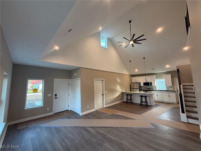 14501 Kennerdown Ave, Maple Heights, OH 44137 - unfurnished living room featuring high vaulted ceiling, a ceiling fan, dark wood-type flooring, and healthy amount of natural light