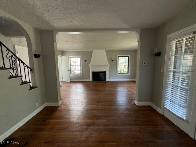 unfurnished living room with a textured ceiling, a fireplace, plenty of natural light, and hardwood / wood-style floors