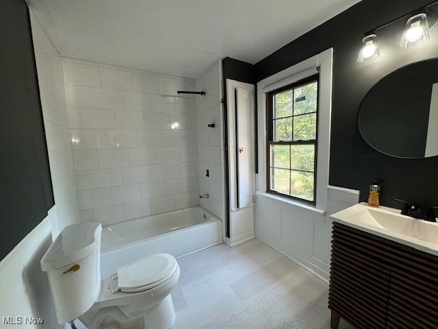 full bathroom featuring vanity, tiled shower / bath combo, and toilet