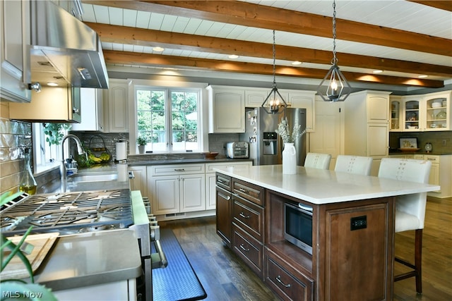 kitchen with tasteful backsplash, wall chimney range hood, a kitchen island, stainless steel fridge with ice dispenser, and white cabinetry