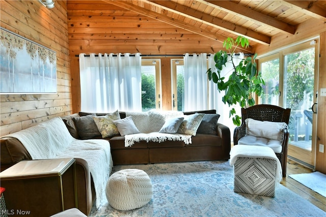 living room with plenty of natural light, wood walls, lofted ceiling with beams, and wooden ceiling