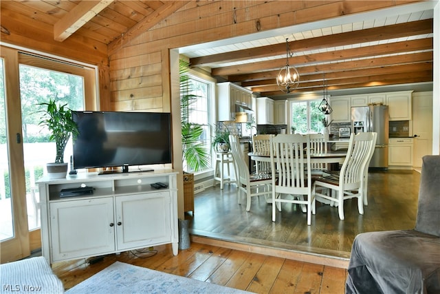 living room featuring hardwood / wood-style floors, an inviting chandelier, a healthy amount of sunlight, and vaulted ceiling with beams