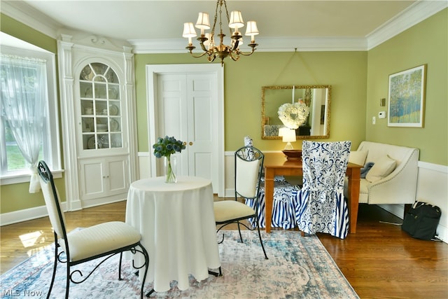 dining area with a notable chandelier, wood-type flooring, and crown molding