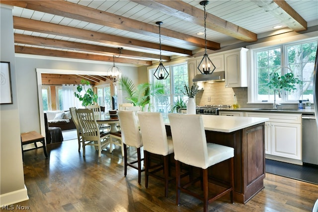 kitchen with beamed ceiling, tasteful backsplash, sink, pendant lighting, and dark hardwood / wood-style flooring