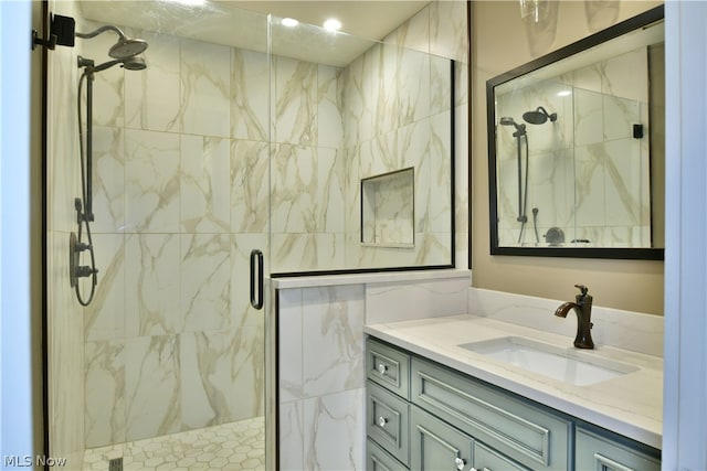 bathroom with a shower with shower door and vanity