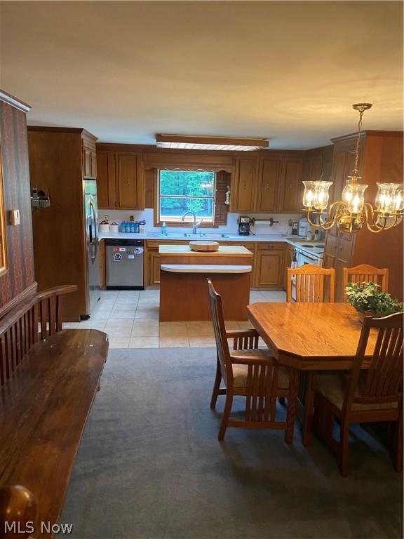 kitchen with appliances with stainless steel finishes, a notable chandelier, pendant lighting, and light tile patterned floors