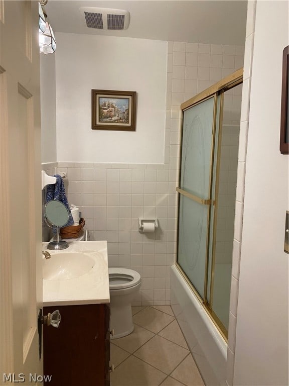 full bathroom with enclosed tub / shower combo, tile walls, toilet, vanity, and tile patterned flooring