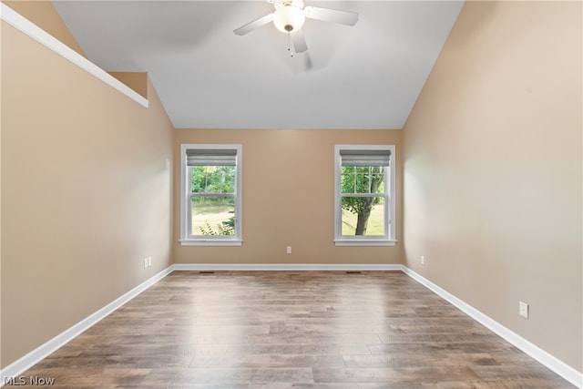 spare room with a wealth of natural light, ceiling fan, wood-type flooring, and vaulted ceiling