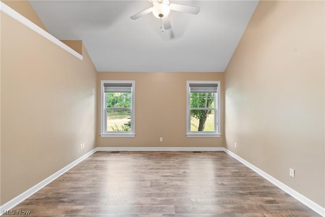 spare room with a healthy amount of sunlight, lofted ceiling, and hardwood / wood-style floors