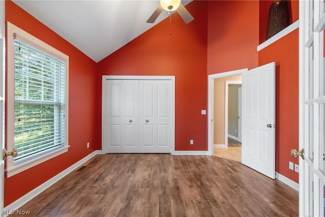 unfurnished bedroom with hardwood / wood-style flooring, a closet, high vaulted ceiling, and ceiling fan