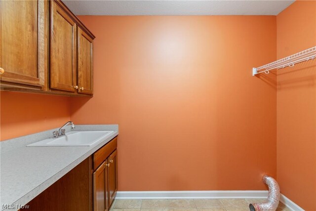 washroom with light tile patterned flooring, sink, and cabinets