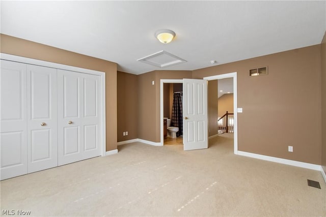 unfurnished bedroom featuring light colored carpet, connected bathroom, and a closet