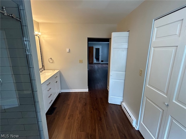 bathroom with hardwood / wood-style flooring, a baseboard radiator, and vanity