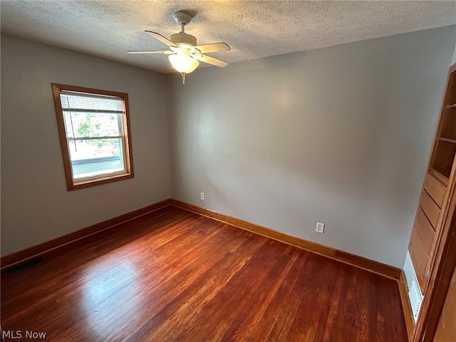 spare room with dark hardwood / wood-style flooring, ceiling fan, and a textured ceiling