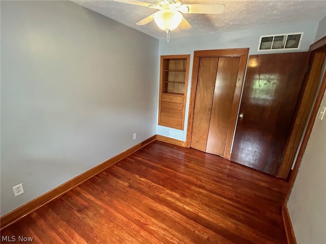 unfurnished bedroom with dark hardwood / wood-style floors, a textured ceiling, and ceiling fan